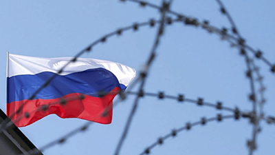 Флаг России за колючей проволокой санкций